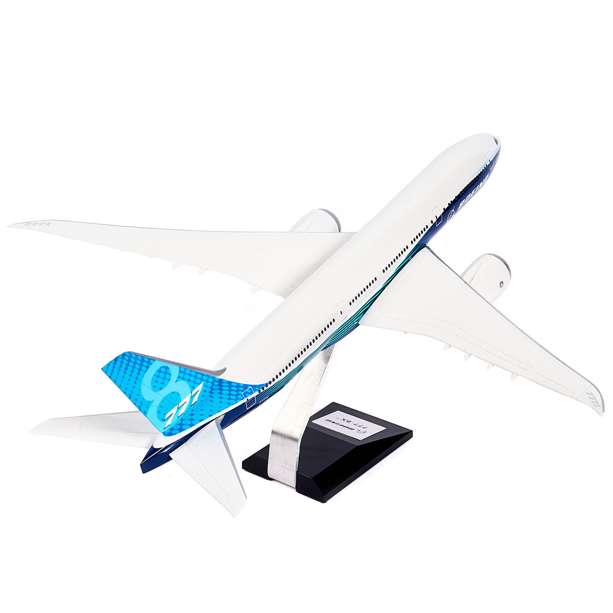 The Boeing Unified 777-8 1:144 Model from The Boeing Store features sleek blue tail accents and wide wings, suggesting a modern twin-engine jet. It is mounted on a stand with an adorned base.