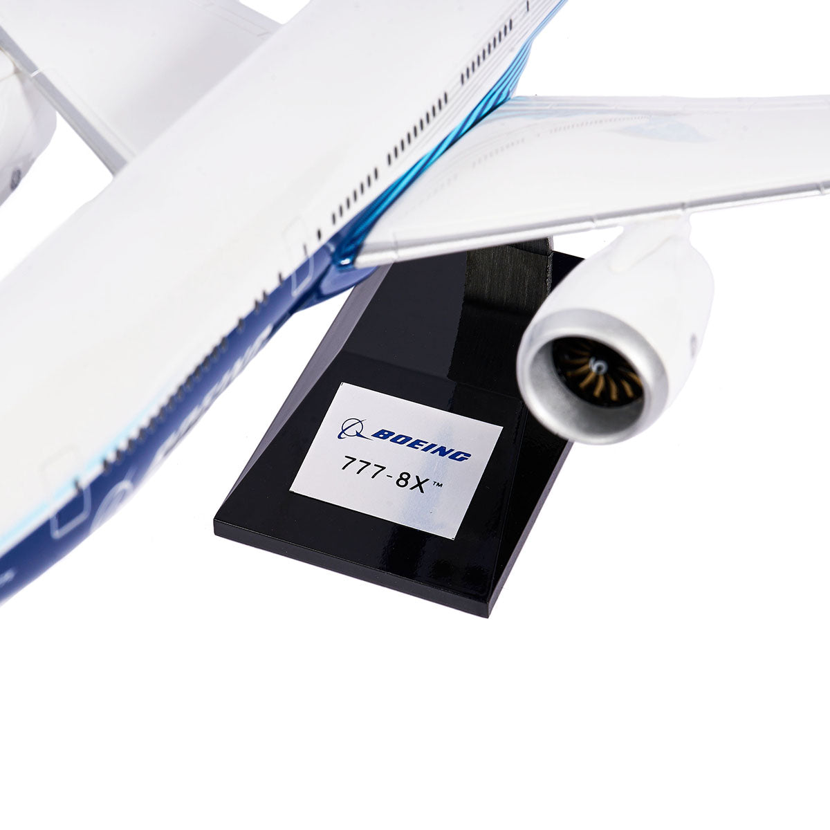Close-up of a sleek Boeing Unified 777-8 1:144 Model on a stand, featuring the engine and wing. The Boeing Store stand shows the iconic logo and reads 777-8X, capturing this twin-engine jets elegance in white with blue accents.