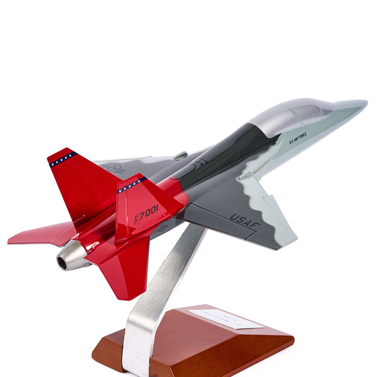 The Boeing Store’s Boeing T-7A Red Hawk 1:48 Model features silk screen printed “USAF” details, a gray body with vibrant red tail fins, and is mounted on a wooden base with metal arm, angled like the iconic Tuskegee Airmen jet.