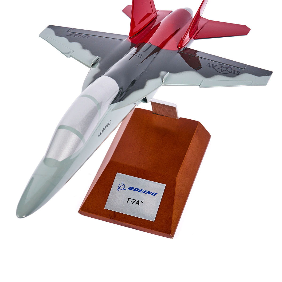 The Boeing Store’s Boeing T-7A Red Hawk 1:48 Model features a red and gray design, USAF markings, and comes mounted on a wooden stand with a Boeing T-7A plaque—honoring the Tuskegee Airmen’s legacy.