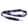 The Boeing Stores navy blue Boeing 747 Motion Lanyard features white 747 sublimation print and airplane graphics, with a black plastic buckle and silver metal clip. This aviation-themed item is displayed flat on a white background.