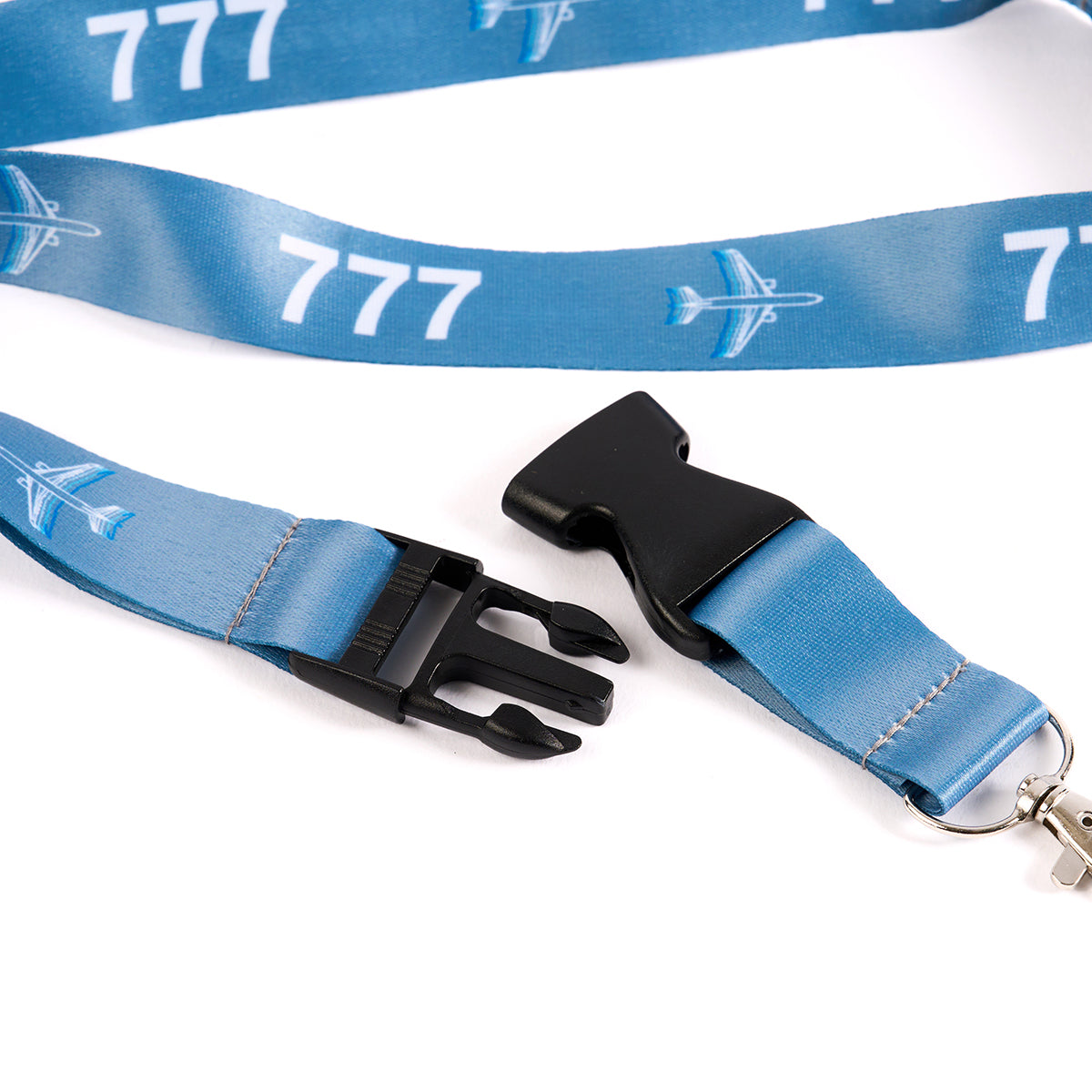 The Boeing Stores Boeing 777 Motion Lanyard is blue with a plastic buckle, featuring an aviation-inspired sublimation print and airplane graphics. Its unclipped with a keyring attachment visible on the right.