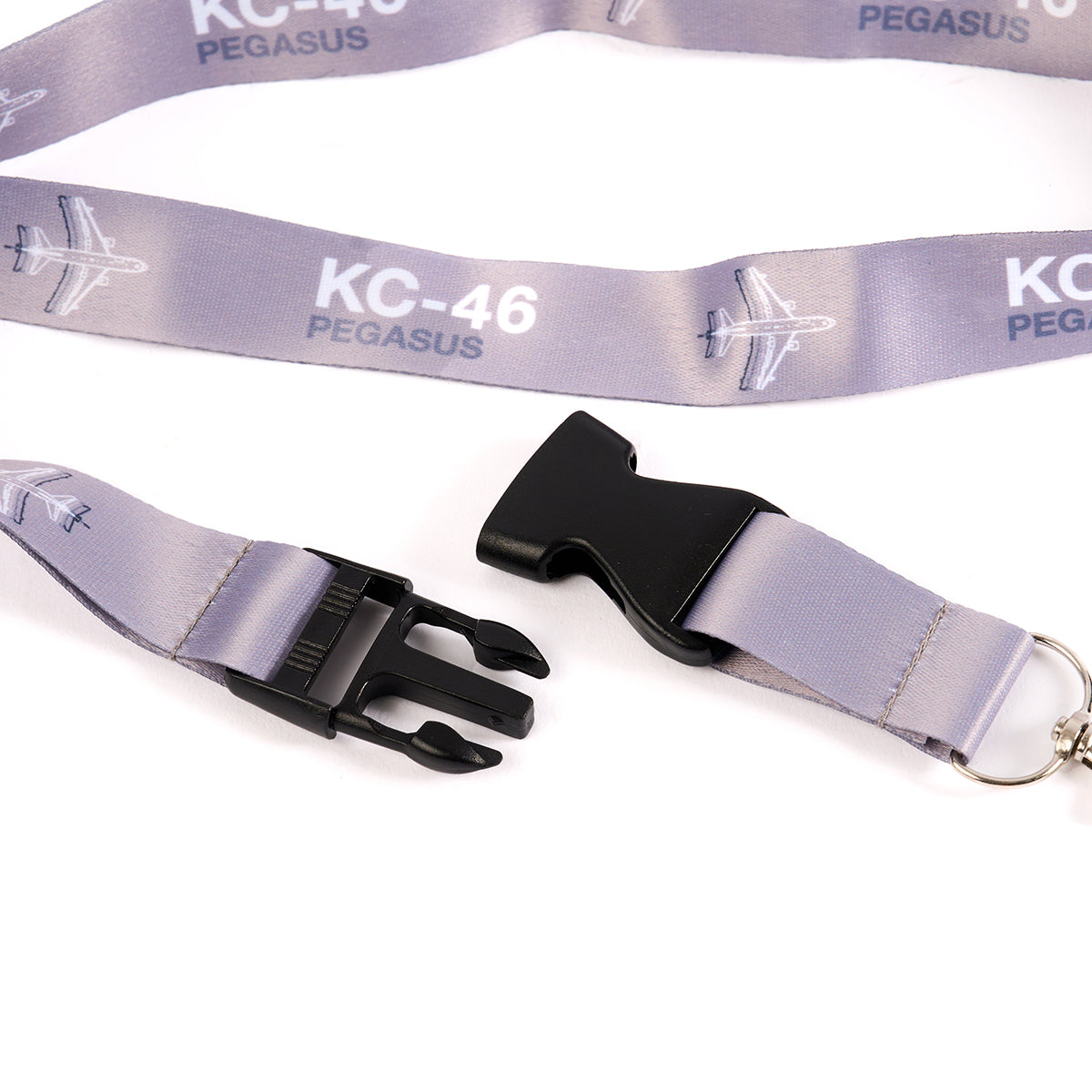 The Boeing Store presents the Boeing KC-46 Pegasus Motion Lanyard in purple with aviation-themed KC-46 PEGASUS and airplane designs. It features black plastic buckles and a metal key ring, ideal for Boeing fans.