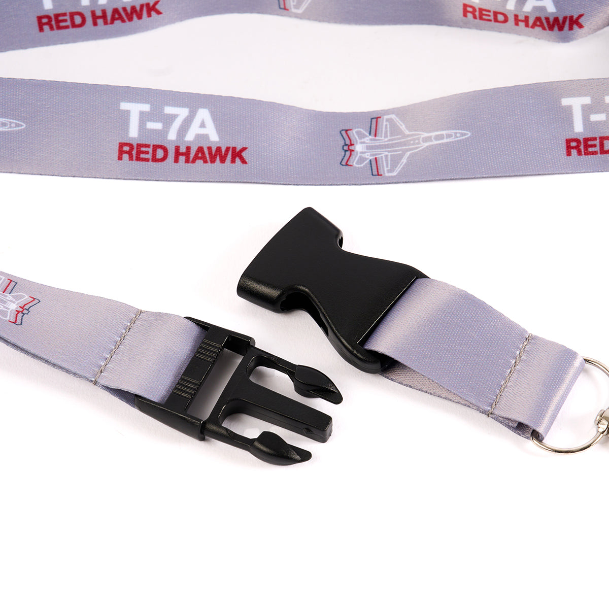 The Boeing Stores T-7A Red Hawk Motion Lanyard, inspired by aviation, features a gray design with the T-7A Red Hawk and jet graphics. It includes a black plastic buckle clasp and metal ring attachment, making it perfect for enthusiasts.