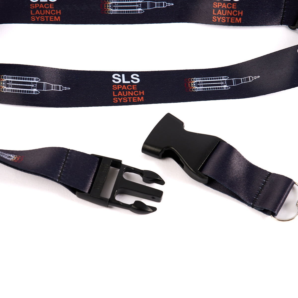 The Boeing Space Launch System Motion Lanyard from The Boeing Store features SLS text and rocket graphics on a dark strap with an aviation-inspired design, highlighted by a black plastic buckle clasp shown detached on a white background.