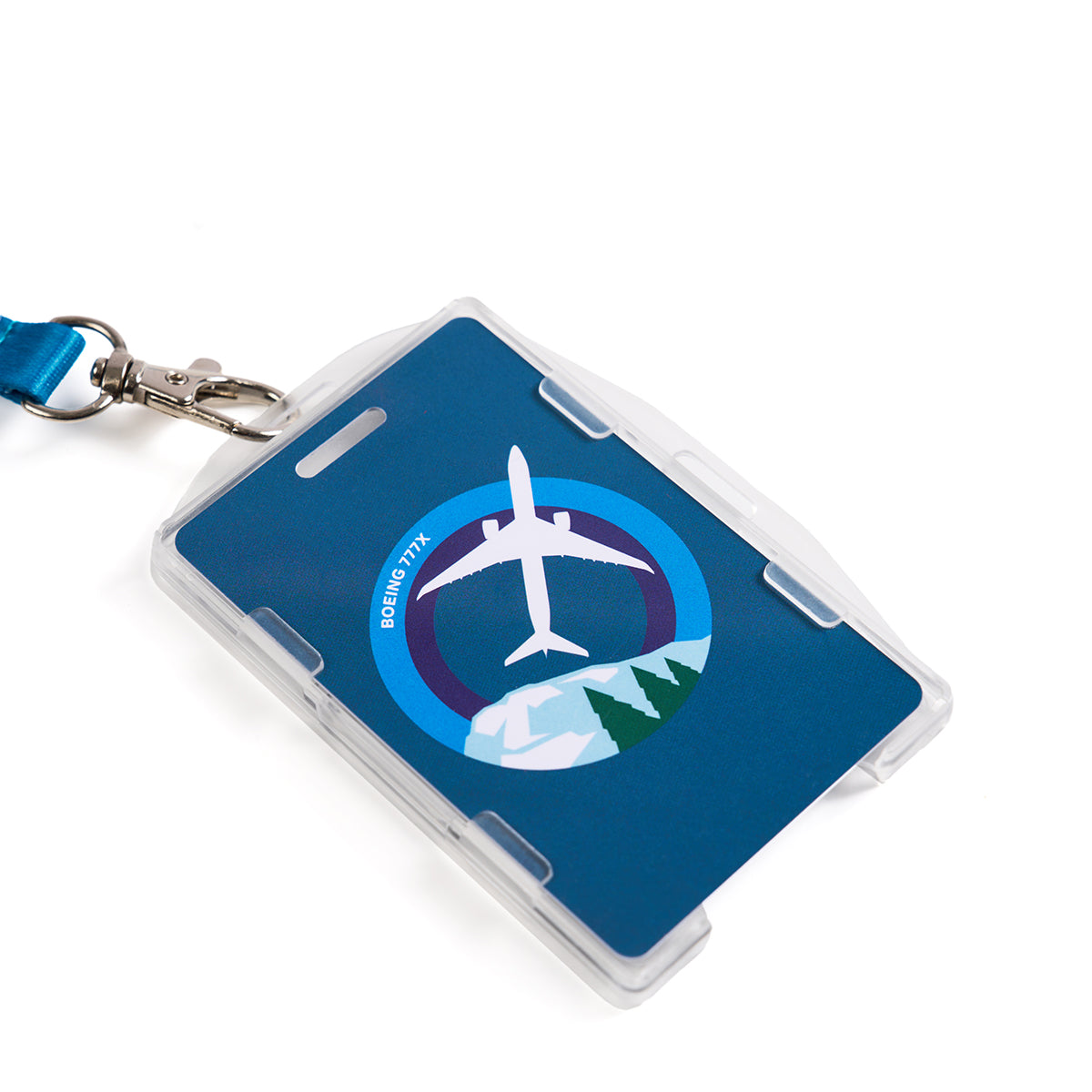 The Boeing 777X Skyward Lanyard by Boeing features a blue cardholder with vivid sublimation print, showcasing a white airplane graphic over circular blue and green designs. A sturdy metal clip seamlessly joins the lanyard to the cardholder.