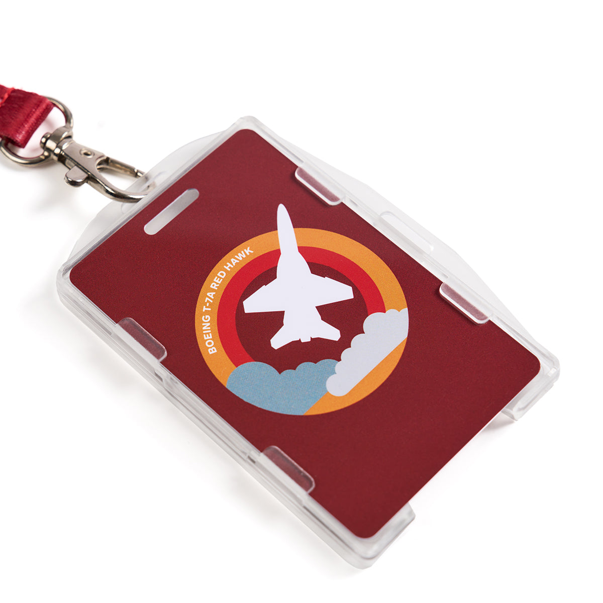 A lanyard called the Boeing T-7A Red Hawk Skyward features a red ID badge with a sublimation print of a jet flying through clouds, surrounded by orange and yellow bands. Text reads Boeing T-45ED Hawk.