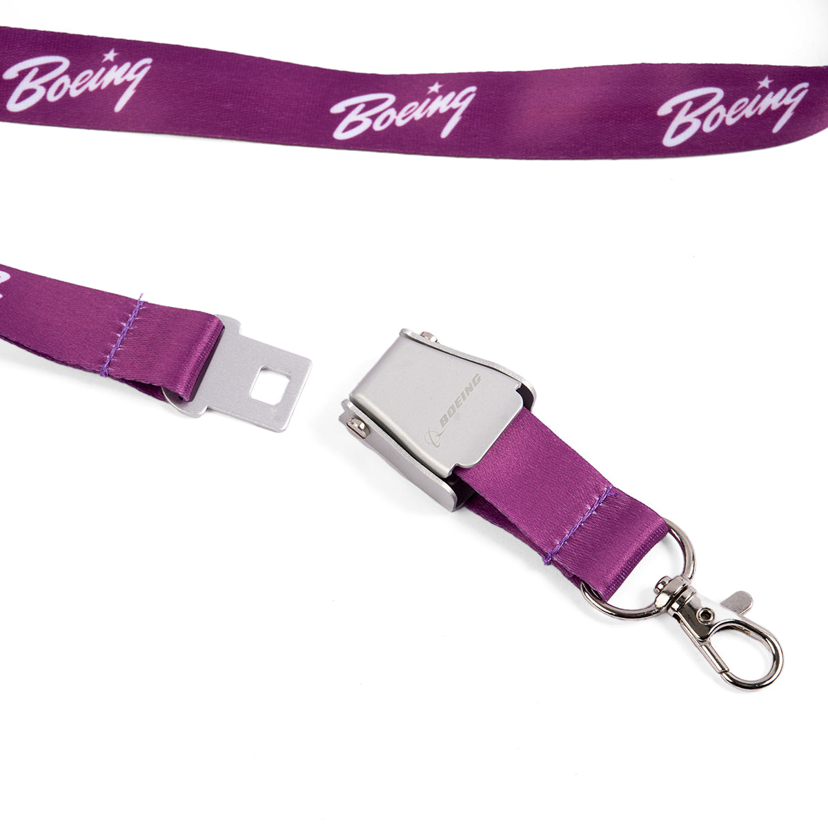 The Boeing Signature Purple Seat Belt Buckle Lanyard features a durable polyester strap with the Boeing logo in white, a metal clasp, and a silver clip. Its vibrant purple color and design are reminiscent of the sleek style and function of a Boeing seatbelt buckle.