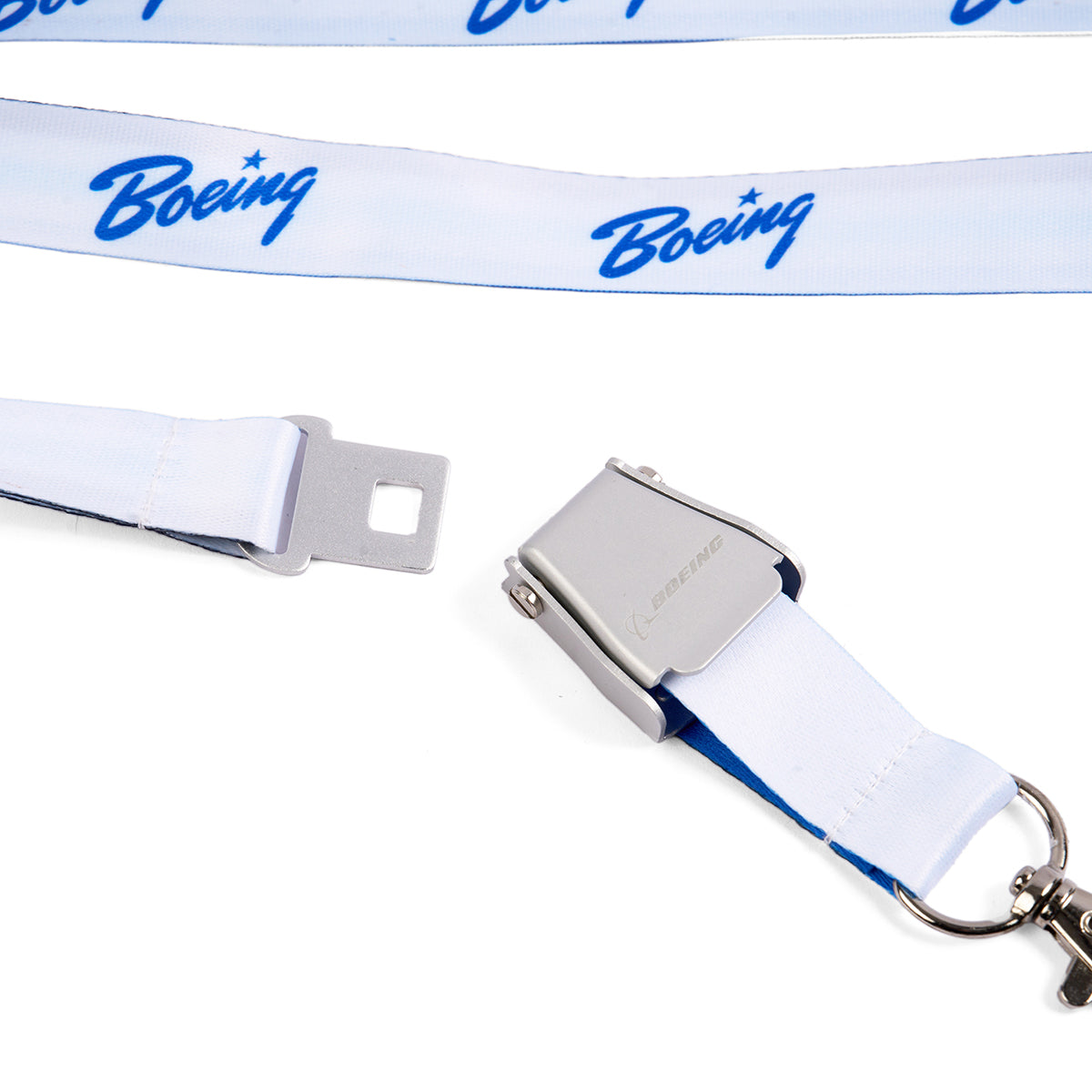 Close-up of a Boeing Signature Blue Seat Belt Buckle Lanyard featuring a metal airplane seatbelt buckle clasp. The white polyester strap displays the blue Boeing logo, with a portion of the lanyard in view.