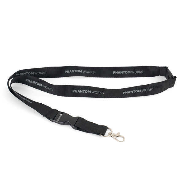 The Boeing Phantom Works 2025 Lanyard by BOEING features black fabric with white lettering, a breakaway clasp, and a metal swivel hook—perfect for aviation accessories enthusiasts.