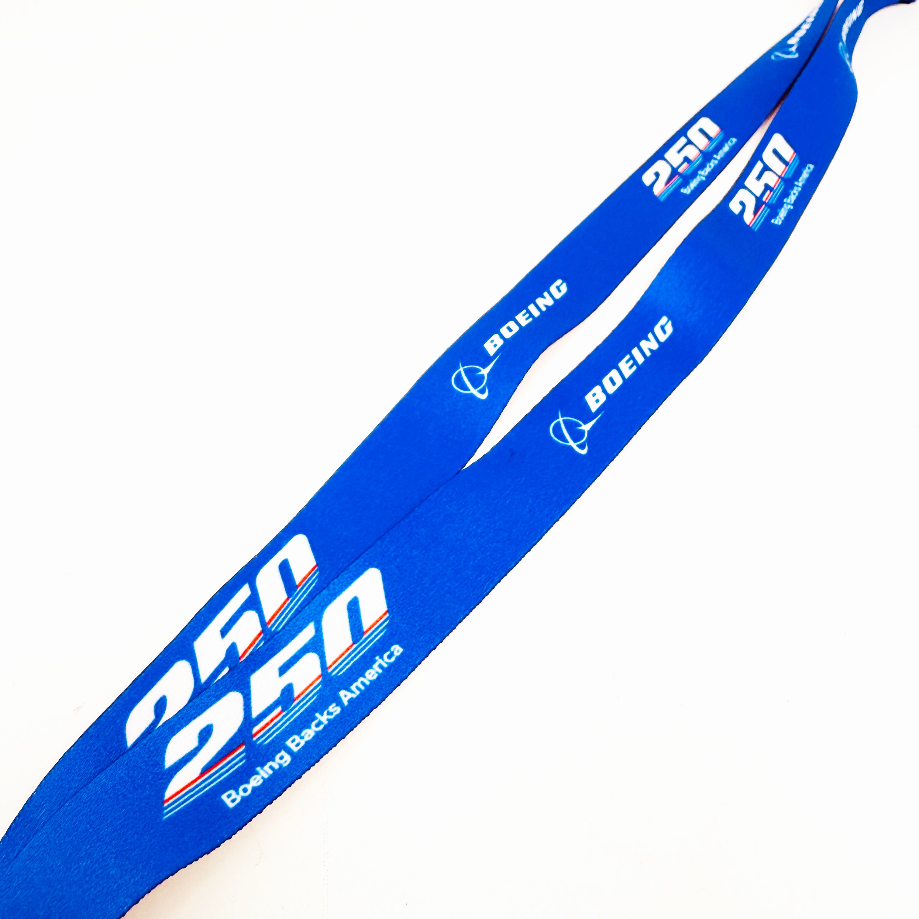 The Boeing America 250 Lanyard by BOEING is a blue lanyard and badge holder featuring the Boeing logo and "America 250 Boeing Back America" printed in white and orange.