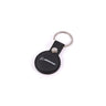 The Boeing Stores black leather Air Tag Holder doubles as a keychain with a round holder. It attaches to a silver metal keyring, featuring a white BOEING logo and text, creating an elegant look against its plain white background.