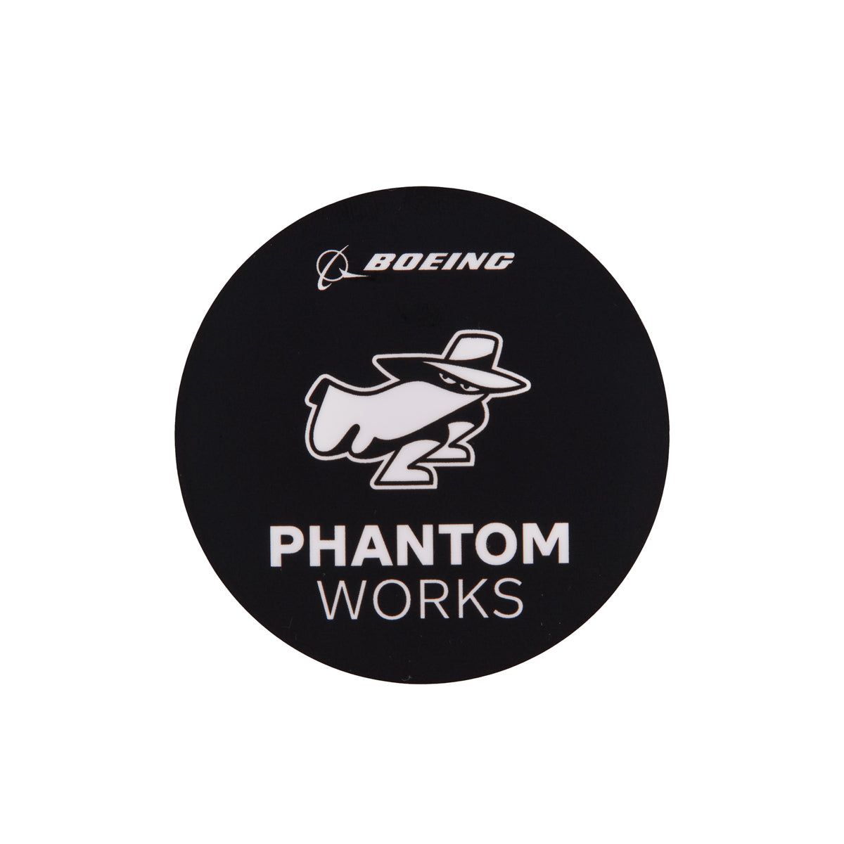 The Boeing Phantom Works Sticker from The Boeing Store features a black circular logo with BOEING at the top and PHANTOM WORKS at the bottom, centered around a stylized white spy figure. Its a perfect vinyl sticker for aviation enthusiasts or fans of Boeing Phantom Works.