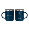 Two dark blue Hydroflask Boeing Coffee Mugs from The Boeing Store sit side by side showcasing TempShield™ insulation. One mug has the Boeing logo, the other displays the Hydro Flask logo, while both insulated mugs have silver rims and black lids for superior temperature retention.