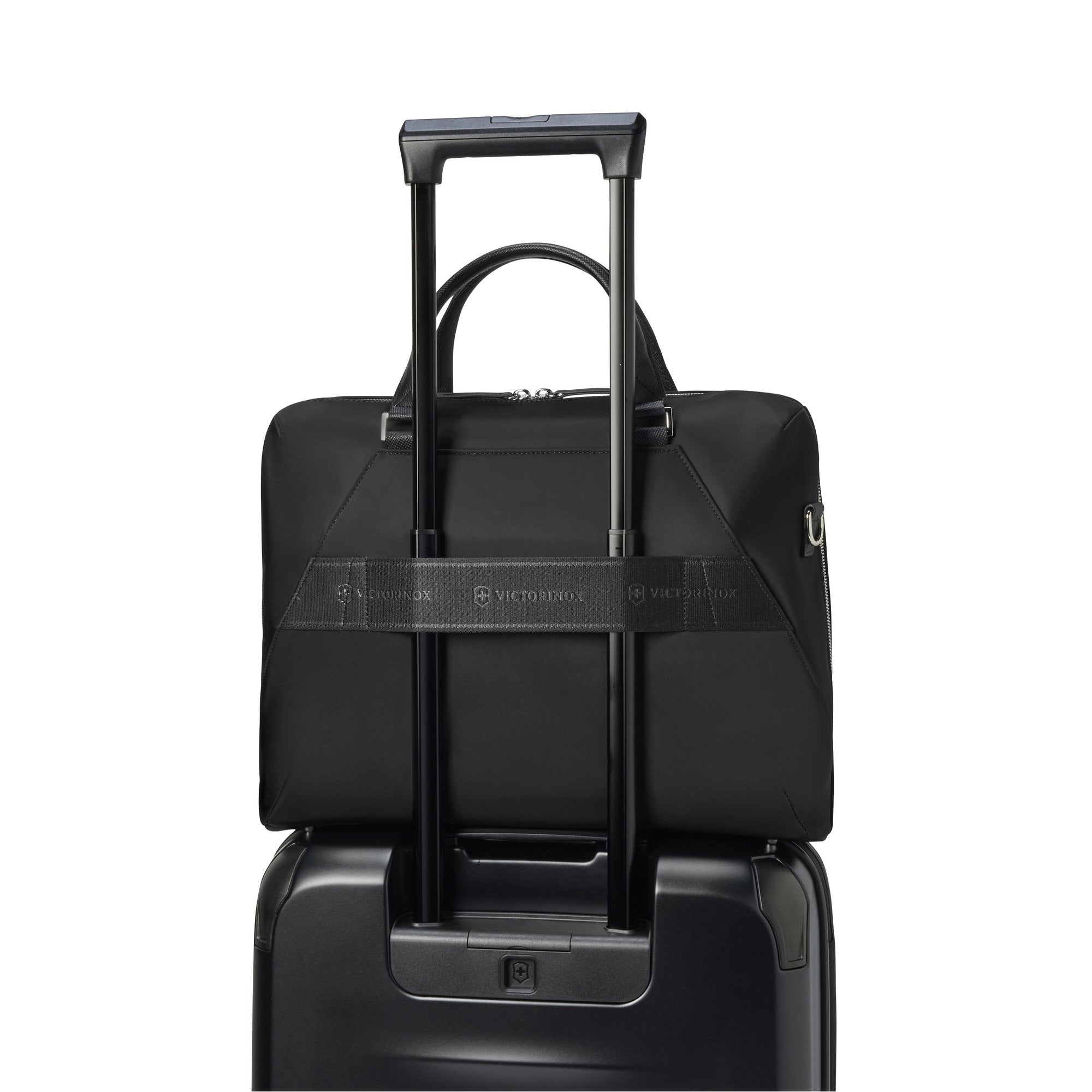 The Victorinox Victoria Signature Briefcase, featuring a sleek black design and the VICTORINOX logo on its strap, attaches seamlessly to an upright suitcase handle. Its 2-in-1 style with a telescopic handle is set against a plain white background, highlighting its versatility.