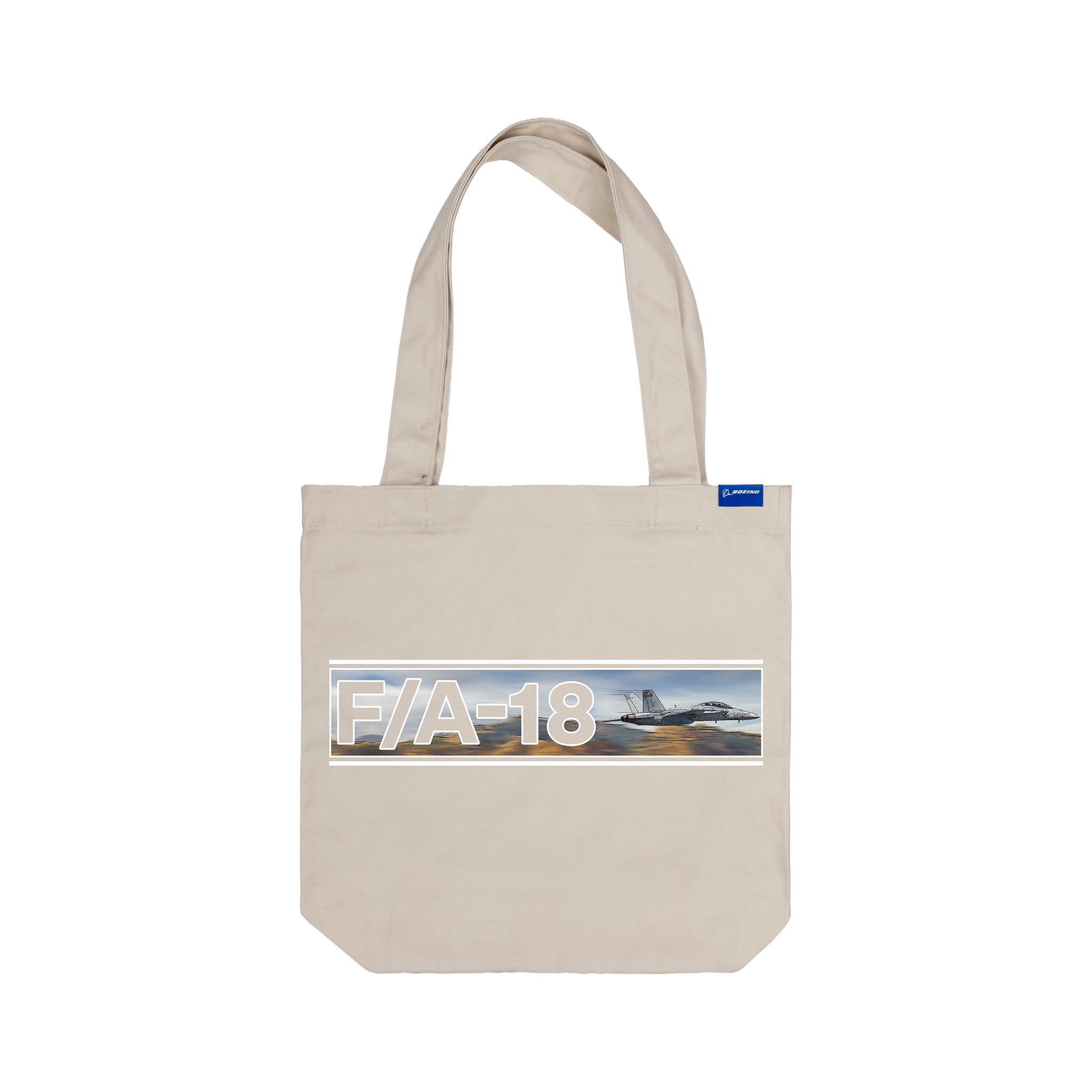 The BOEING F/A-18 Super Hornet Graphic Tote is a beige bag with bold F/A-18 text, a blue sky and runway design, plus a small blue tag—ideal for aviation enthusiasts.