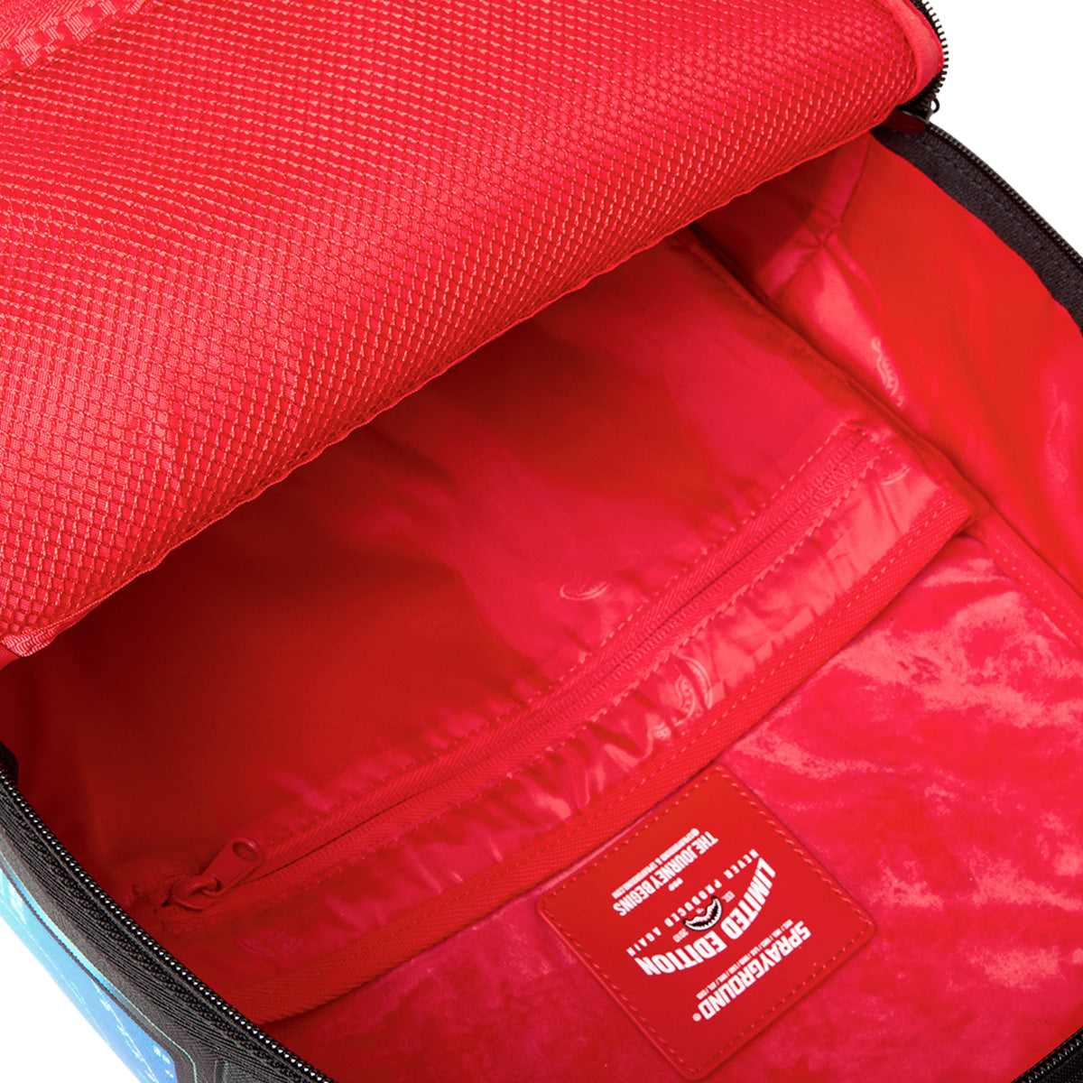 Open the Sprayground Boeing F/A-18 Super Hornet DLXSR Backpack by BOEING to reveal a vibrant red interior, complete with a zippered pocket and a label displaying "Sprayground Limited Edition" in white text. Inspired by the iconic F/A-18 Superhornet, this stylish backpack also offers a dedicated laptop compartment to keep your essentials organized while you're on the move.