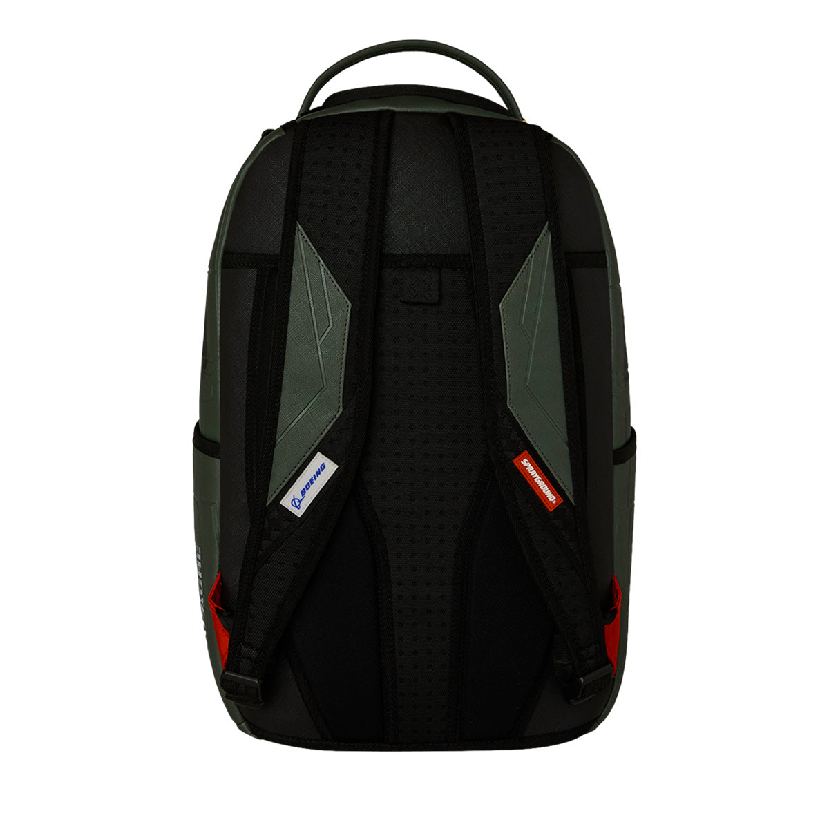 The Sprayground Boeing AH-64 Apache Sharkmouth DLXSV Backpack by BOEING is shown from the back in black and dark green, featuring two padded shoulder straps with small blue and red tags, a top handle, and red accents on the lower sides. This backpack highlights bold tactical styling for a rugged yet modern appearance.