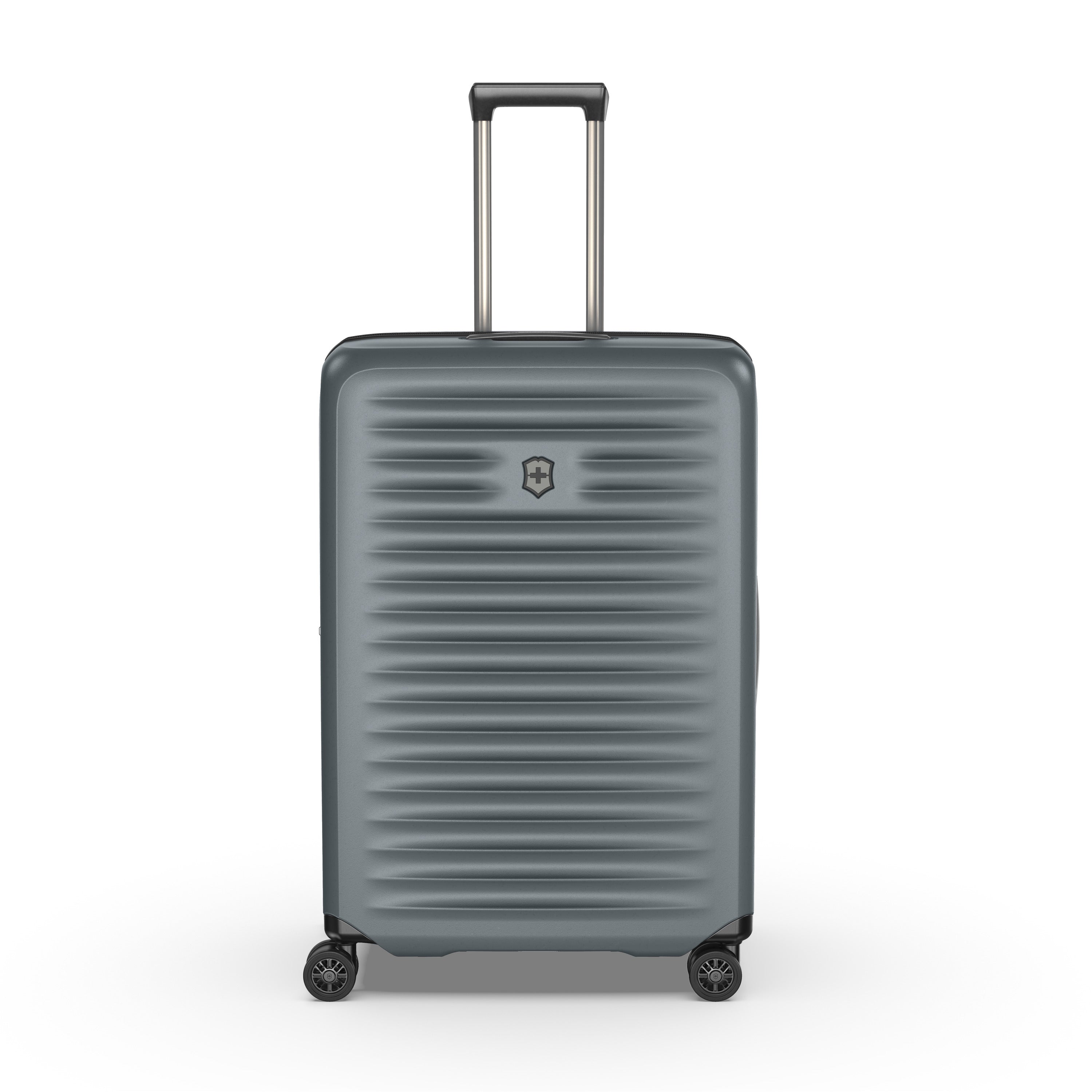 The Victorinox Airox Advanced Large - Storm suitcase features a sleek gray design with ribbed texture, four black wheels, and an extending silver telescopic handle showcasing Swiss engineering. The VICTORINOX logo is on the front center as the lightweight luggage stands upright against a white background.