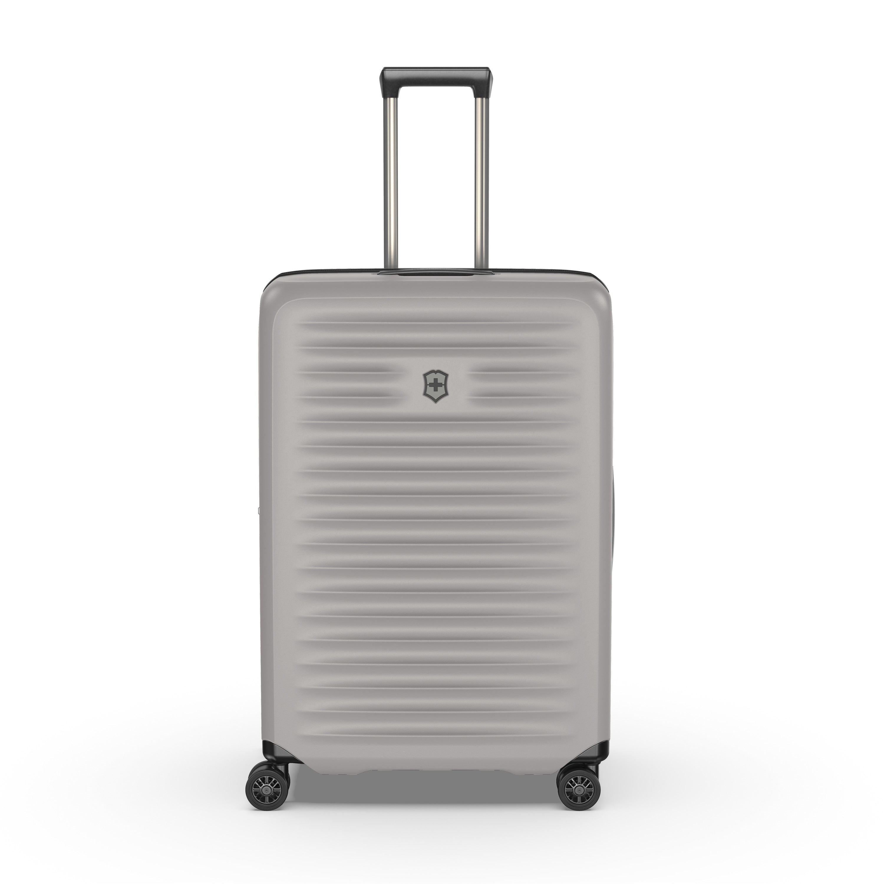 Meet the VICTORINOX Airox Advanced Large - Stone: a sleek suitcase featuring a grey hard shell with horizontal ridges, telescopic handle, and four spinner wheels. Its anti-microbial interior ensures cleanliness, while the brand logo is prominently displayed on the front against a plain white background.