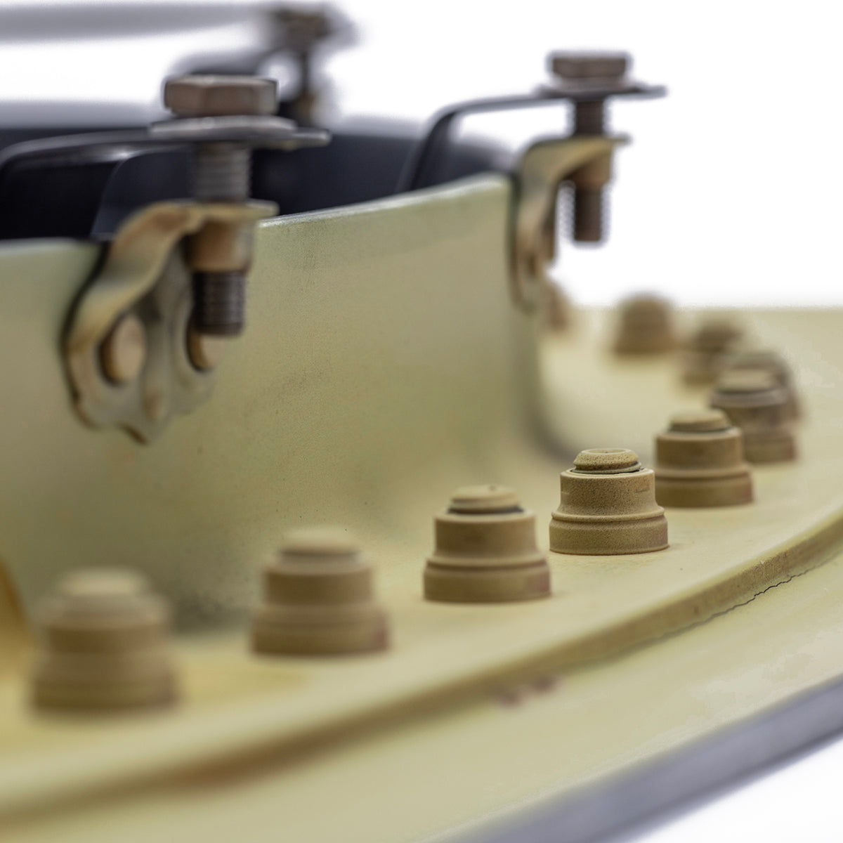 Close-up of metal bolts and screws on a curved, light yellow Boeing 777 Natural Finish Window, with a shallow depth of field highlighting the front row of fasteners.