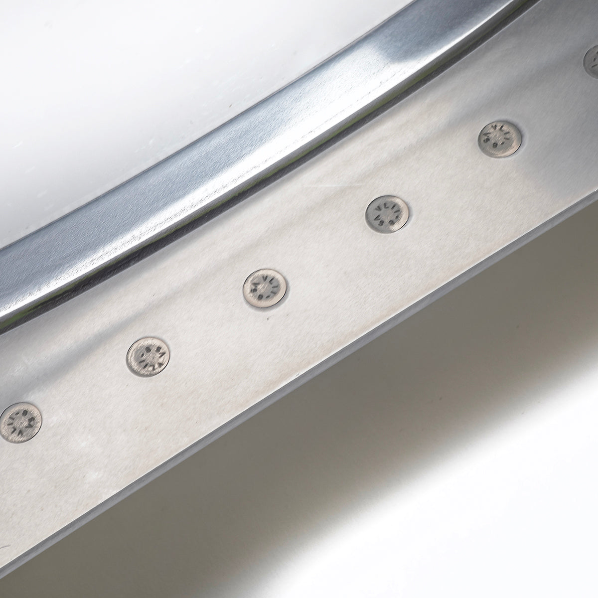 Close-up of a Boeing 777 Natural Finish Window by Boeing shows several round, evenly spaced fasteners and a curved, polished edge reflecting light for a sleek, industrial look.