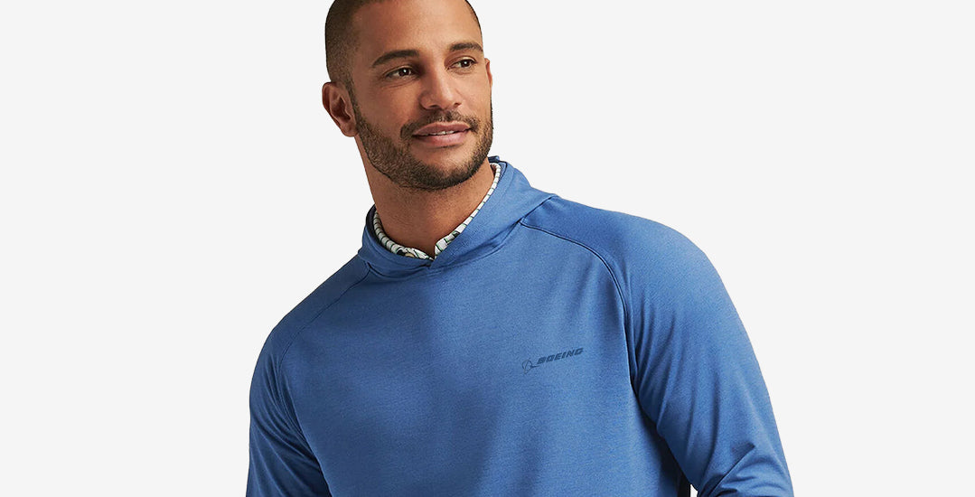 A male model dressed in a blue long-sleeve hoodie, showcasing a casual look against a white background.