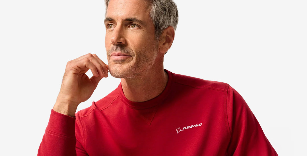 A man wearing a red johnnie-O sweatshirt with the Boeing logo, posed against a neutral background.