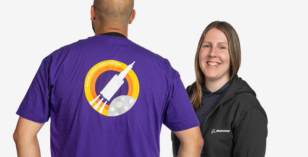 Boeing space program tile for programs LP featuring people wearing  a purple SLS t-shirt from the Skyward collection and  black SLS full-zip hoodie on light grey background.