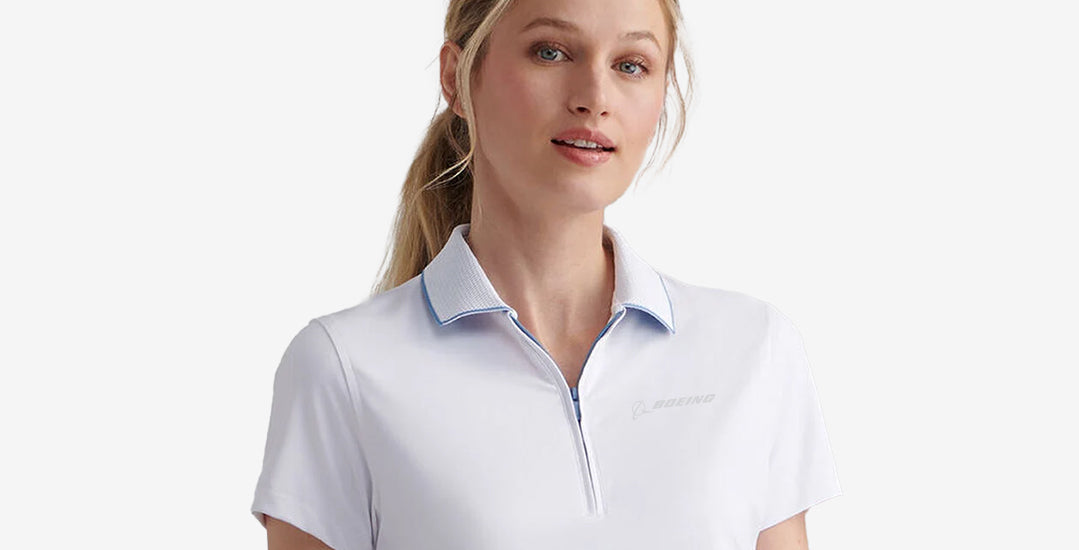 A woman wearing a white Peter Millar polo shirt with a subtle Boeing logo, posed against a neutral background.