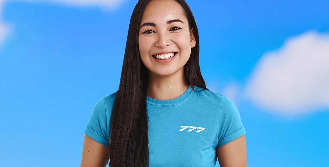 A person wearing a blue Boeing Series T-shirt with the 777 logo on the left chest, standing against a blue sky with clouds.