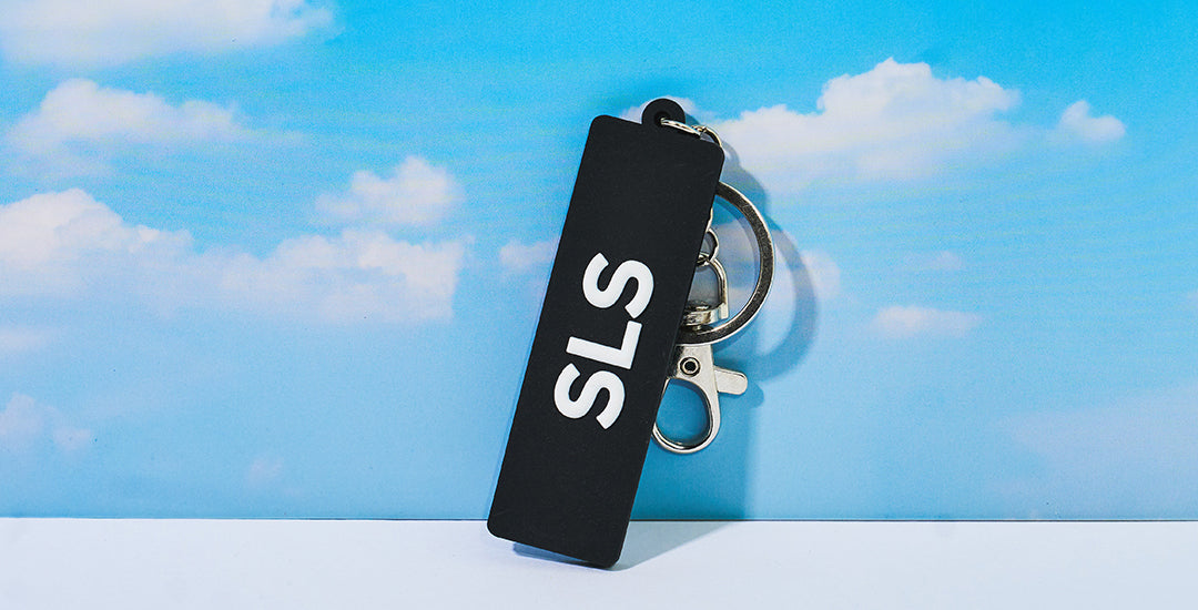 Boeing Series keychain with the SLS logo on the front, against a blue sky with clouds.