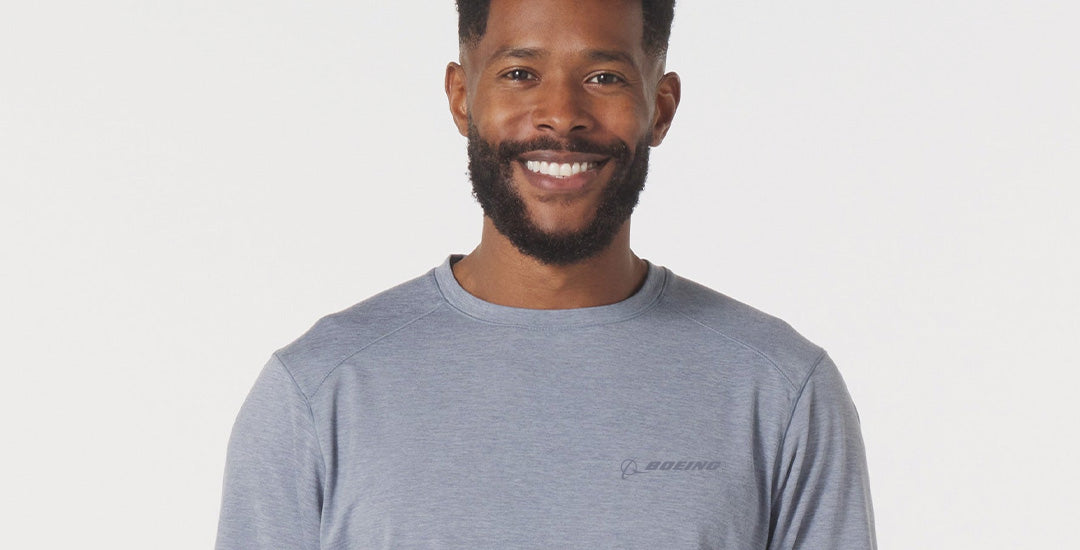 Man wearing a gray crewneck with the Boeing logo on a light gray background