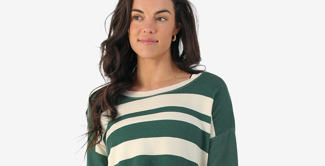 Woman wearing a green and white striped Boeing sweater on a light grey background