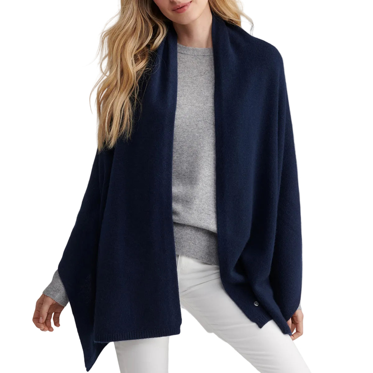 A woman with long, wavy blonde hair models the luxurious Boeing Peter Millar Cashmere Wrap over a light gray sweater and white pants, standing against a plain white background.