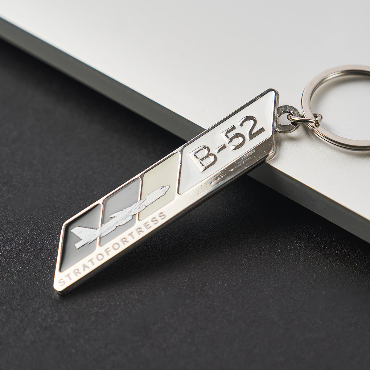 Image of a keychain featuring a B-52 aircraft and logo propped on a desk.