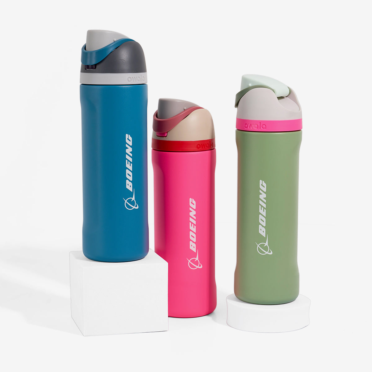 A set of three colorful water bottles with the Boeing logo, displayed on white pedestals against a clean white background.