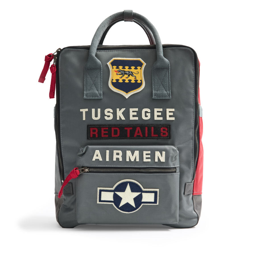 A vintage grey Red Canoe Boeing Tuskegee Red Tails Backpack with top handles, featuring a Tuskegee Red Tails Airmen patch, a panther crest, and a star insignia.