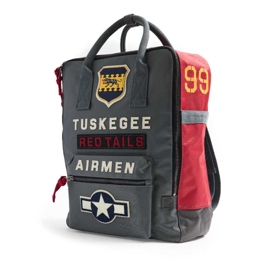 A durable grey and red Red Canoe Boeing Tuskegee Red Tails Backpack featuring Airmen lettering, an Air Force emblem, a panther crest, and the number 99.