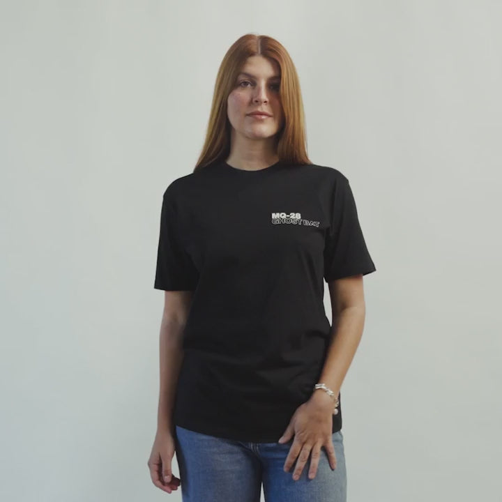 Lifestyle video of woman wearing a MQ-28 T-shirt against a light grey background.