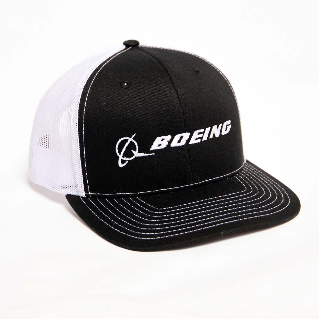 The Richardson Boeing Signature Logo Trucker Hat by The Boeing Store features a white logo on a hat with black front panel, brim, and white stitching. It has white mesh back panels and a snapback closure for an adjustable fit.