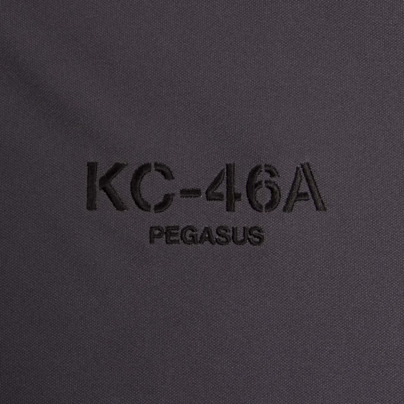 A close-up of black fabric with KC-46A PEGASUS embroidered in dark thread, evoking The Boeing Stores KC-46 Polo.