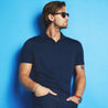 lifestyle image of the product featured on a male model leaning against a blue wall. 