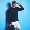 full body product lifestyle image on male model.  Model wear blue camo hat with khaki shorts and standing against blue wall