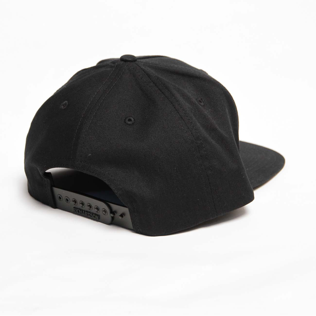 The Richardson Boeing Signature Logo Flat Bill Hat by The Boeing Store features a signature logo, adjustable snapback closure, and ventilation eyelets. Elegantly displayed from the back on a plain white background, this cap blends style with comfort effortlessly.