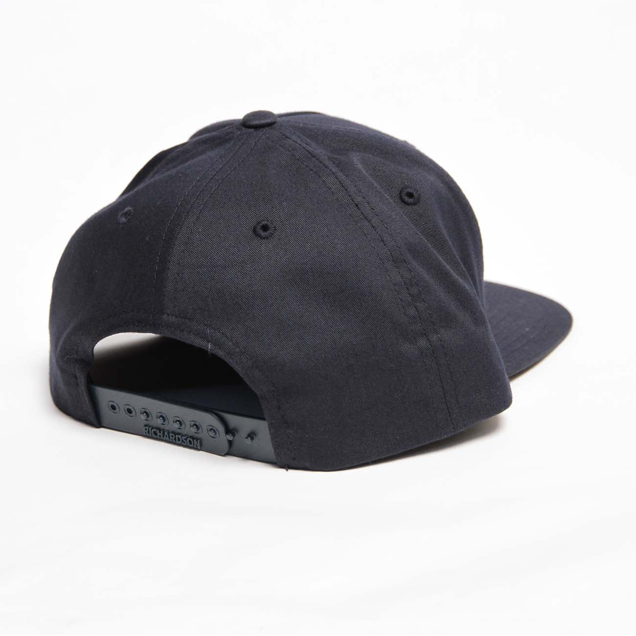 The black Richardson Boeing Signature Logo Flat Bill Hat is displayed from the back, featuring its adjustable Snapback Closure. Set against a white background, it emphasizes the hats minimalist design and texture. Available at The Boeing Store.