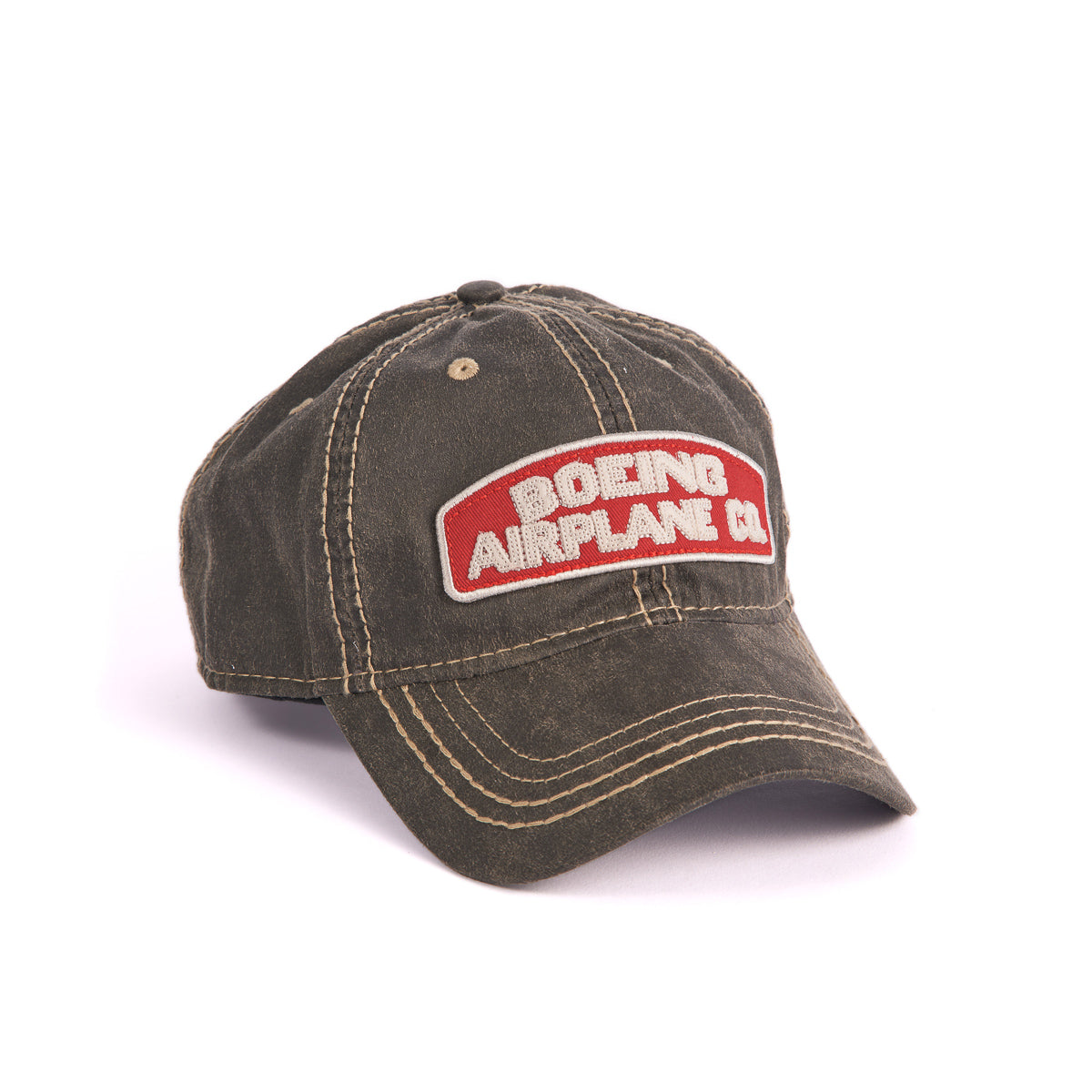 The Boeing Stores Boeing Airplane Co. Heritage Hat is a weathered dark green baseball cap featuring a white-stitched heritage logo, an embroidered red and white patch, a curved brim, and an adjustable velcro strap for a custom fit.