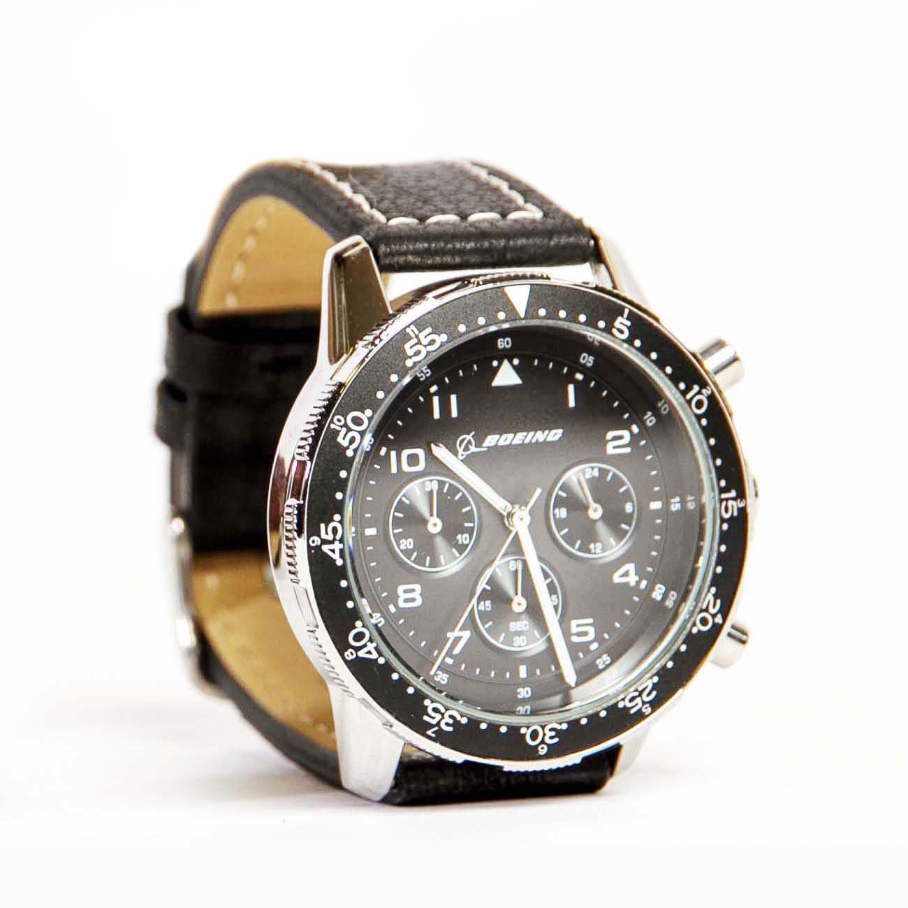The Boeing Stores Boeing Black Leather Watch is a mens analog wristwatch boasting a Japanese movement, a stainless steel case with a black dial, three subdials, white markings including the number 60 at the top, and a tachymetric bezel for precision.