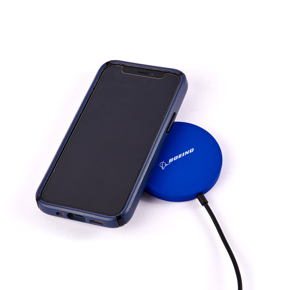 A smartphone in a dark case sits on The Boeing Stores Wireless Magnetic Charger, delivering fast and secure charging on its blue pad, against a plain white backdrop.