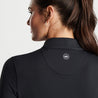 Showing the top half of the backside of the black full zip on a female model.  Peter Millar logo in the center in between the shoulders.
